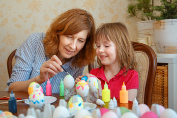Mom and daughter have fun painting eggs for Easter.