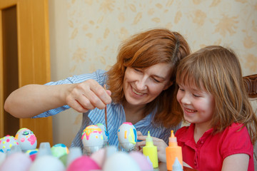 Mom and daughter have fun painting eggs for Easter.