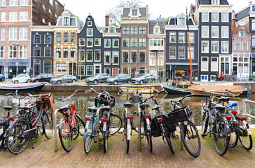 Street in Amsterdam, yachts on the canal and bicycle parking in the foreground close