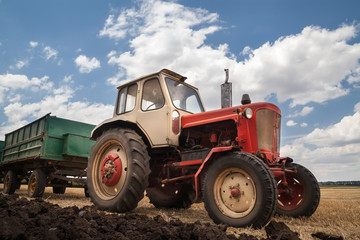 old tractor in field, against a cloudy sky