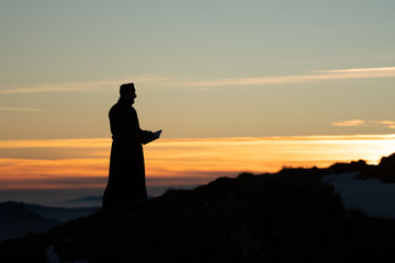 Priest silhoute reading in the sunset light, Romania