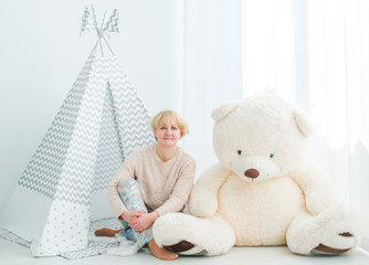 Mature woman sitting on a floor with a toy teddy