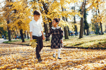 little beautiful dark-skinned girl walks in the autumn park with her European little friend