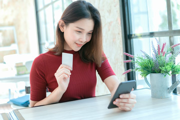 Young woman holding credit card and using smart phone 