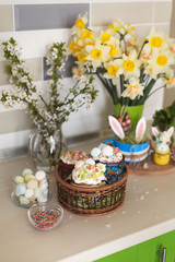 Obraz na płótnie Canvas Easter sweets and decorations eggs with funny bunny on kitchen table