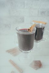 Mulled wine in a beautiful glass. Winter warming drink. Hot mulled wine on the wooden table. Glass of mulled wine with spices. 