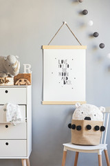 Scandinavian child room with mock up poster frame on the grey wall, white commode, teddy bear and...