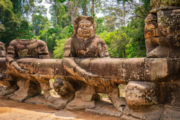 Preah Khan temple, Cabodia: Sculpture of demon holding serpent Vasuki on causeway with railings depicting Churning of the sea of milk of khmer mythology