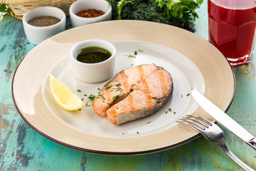 Grilled salmon fillet with soy sauce and slice of lemon on blue wooden table