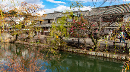 Kurashiki canal in autumn with trees and houses in Japan