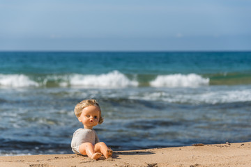 Old Broken Toy Doll Sitting on a Beach in Italy