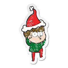 distressed sticker cartoon of a curious boy rubbing eyes in disbelief wearing santa hat