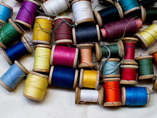 Old multi-colored coils lie in a box. A pile of coils with colored threads. Sewing supplies. Many...