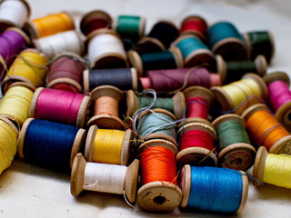 Old multi-colored coils lie in a box. A pile of coils with colored threads. Sewing supplies. Many...