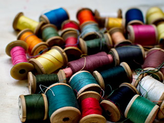 Old multi-colored coils lie in a box. A pile of coils with colored threads. Sewing supplies. Many coils of thread.