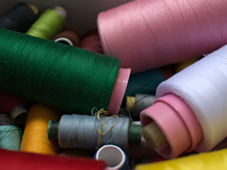 Old multi-colored coils lie in a box. A pile of coils with colored threads. Sewing supplies. Many...