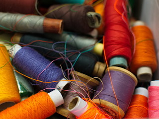 Old multi-colored coils lie in a box. A pile of coils with colored threads. Sewing supplies. Many...