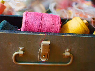 Old multi-colored coils lie in a box. A pile of coils with colored threads. Sewing supplies. Many...