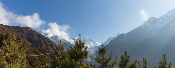 Panoramic view of Mt Everest in the distance with trees sticking up in the foreground. Taken during the hike towards Everest Base Camp. 