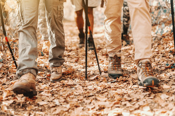 Close up of hiker's feet walking through woods in autumn. Leafs on ground.