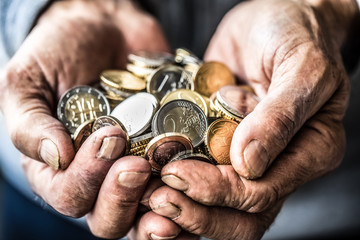 Pensioner man holding in hands euro coins. Theme of low pensions