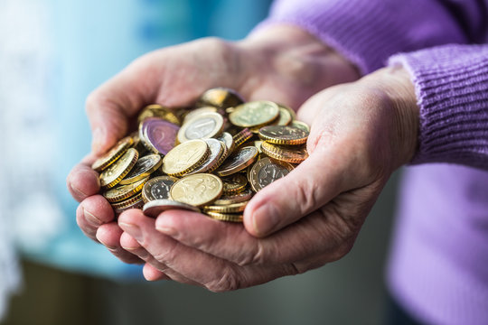 Pensioner woman holding in hands euro coins. Theme of low pensions