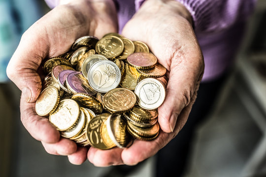 Pensioner Woman Holding In Hands Euro Coins. Theme Of Low Pensions