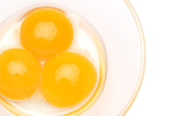 three egg yolk in a glass bowl isolated on white background