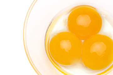 three egg yolk in a glass bowl isolated on white background