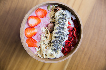 Berries smoothie bowl with strawberry and banana and godi ceed on wooden table.
