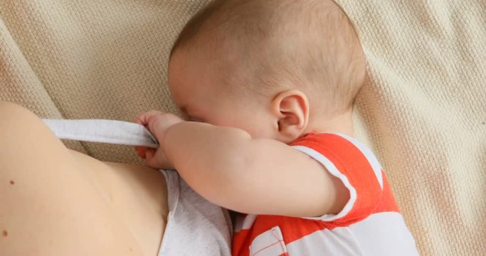 mother breastfeeding and hugging baby, close-up breast. Mom breast feeding her newborn child. Lactation infant. Baby eating milk before he sleeping. Mother feed her two month baby son with breast milk