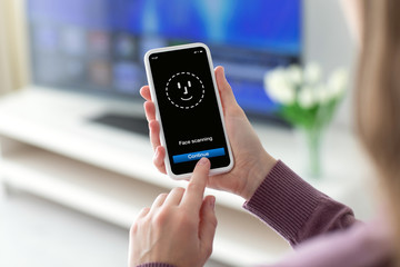 Female hands holding phone with face ID scanning on screen