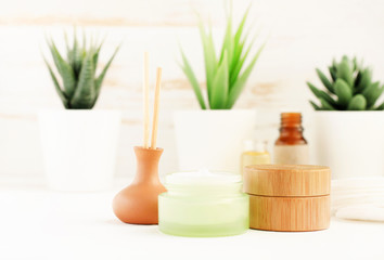 Obraz na płótnie Canvas Homemade spa set, bath shelf with cream jars, essential oils, green plants background, light minimalist eco decor. 