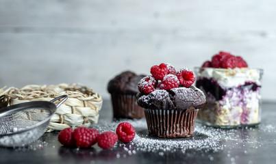 chocolate muffin with fresh raspberries sprinkled with powdered sugar in a rustic kitchen
