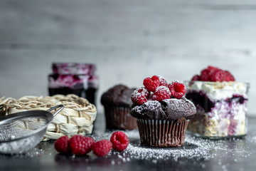 chocolate muffin with fresh raspberries sprinkled with powdered sugar in a rustic kitchen