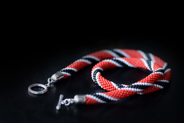 Bead crochet necklace red, black and white colors on a dark background close up