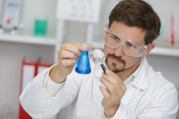 scientist using a magnifying glass in a test tube