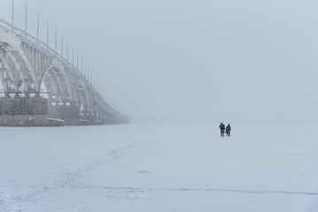 Classic winter landscape - a bridge in the fog on a frozen river