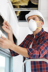 worker climbing into loft to insulate house roof