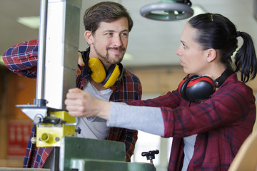 female worker using industrial machine under supervision