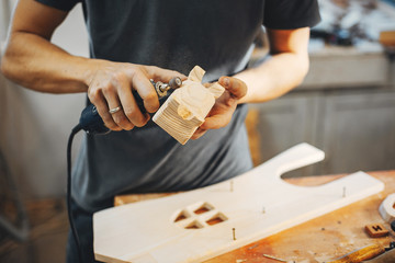 A man carves a tree. The carpenter works in a studio. An engineer provides a tree shape