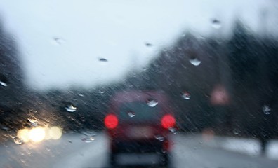 Driving a car after a rainy afternoon. Blurred view through the rear window of a car.