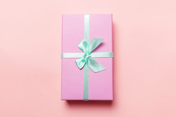 Christmas New Year birthday valentine celebration present romantic concept. Small gift box wrapped pink paper isolated on pink pastel colorful trendy background. Flat lay top view copy space