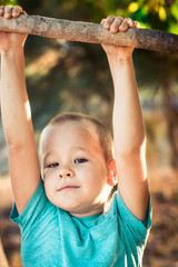 Fototapeta na wymiar Little boy swinging on a tree