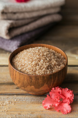 Sea salt and colorful towels with coral azalea flowers on rustic wooden background.