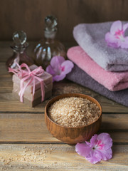 Sea salt, natural handmade soap, natural cosmetic oil and colorful towels with azalea flowers on rustic wooden background