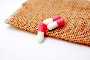 white pink capsules on a small jute background