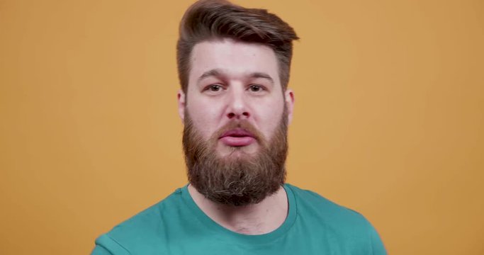 Young bearded man swearing and arguing with someone. During a fight with an enemy. Saying bad words to another person.