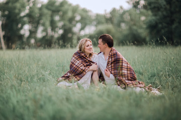 happy, married couple sitting together under a warm blanket on the lawn