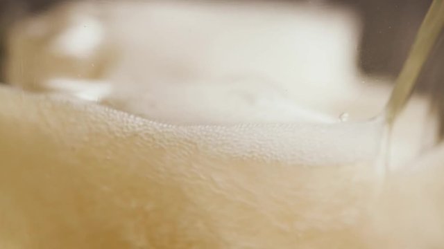 Macro light beer pouring into a glass with ascending bubbles